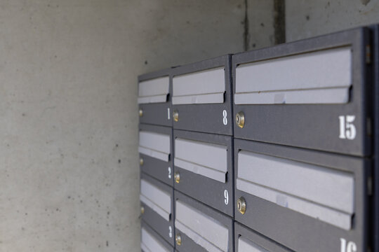 Close-up view of a wall-mounted bank of numbered apartment mailboxes in a concrete residential building entrance, postal boxes for letters and correspondence
