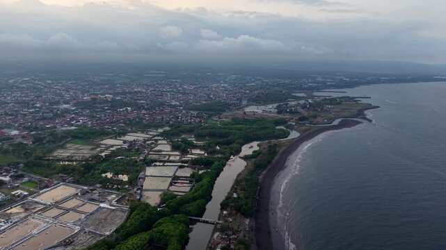 Aerial coastal panorama of Pantai Boom showing mangroves, salt pans, urban shoreline and moody cloudy sky
