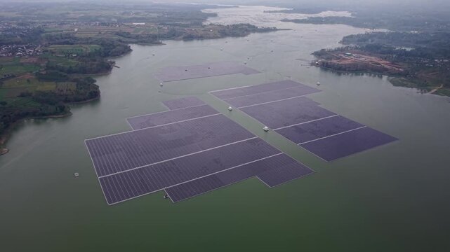 Drone aerial capture of vast floating solar farm on Bendungan Karangkates reservoir near agricultural landscape