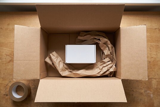 Small product box inside oversized shipping carton with excess paper packaging