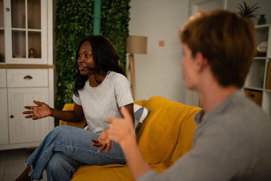 Interracial couple having serious discussion on sofa at home