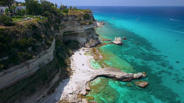 Tropea Calabria Italy 4k drone view of secluded beach and white vertical cliffs. Flyby along clear turquoise emerald sea with boulders b-roll untouched nature Costa degli Dei scenic video footage