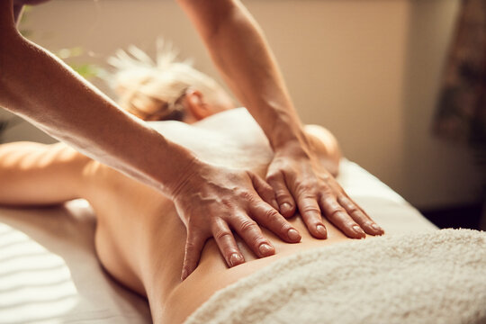 Therapist massaging woman's lower back in spa treatment room