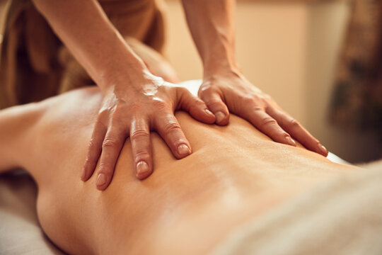 Therapist performing back massage on woman in spa