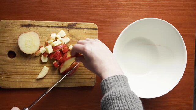 Person Slicing Fresh Red Apples with Kitchen Knife on Rustic Cutting Board