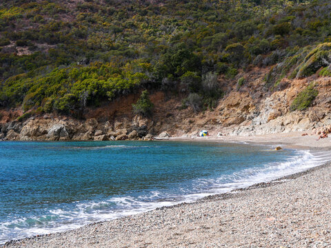 Secluded pebble beach with parasol and clear sea at Girolata gulf Corsica