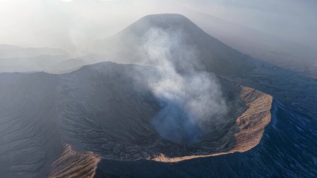 Drone panorama of Mount Bromo steaming crater and surrounding volcanic caldera at sunrise.