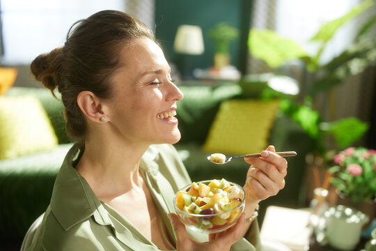 Capturing a moment of joy, a woman enjoys a spoonful of mixed fruit salad, promoting healthy eating habits and the benefits of a balanced diet.
