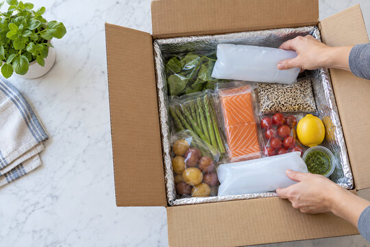 Hands placing cold packs in insulated meal kit box