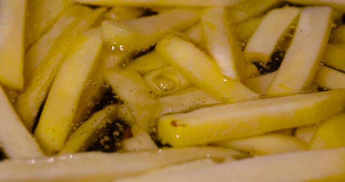 Yellow french fries potato sticks cooking in hot fat, cut raw french fries potato pieces deep fried in boiling oil with air bubbles