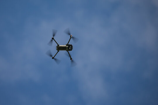 Drone flying in a clear blue sky viewed from below