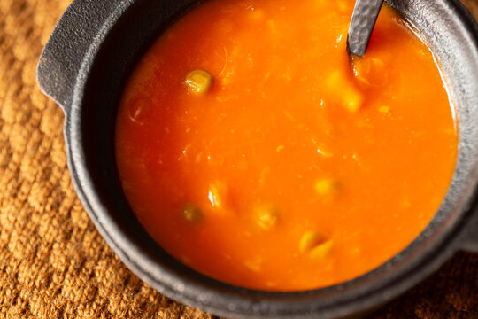 Homemade vegetable soup in a traditional cast iron bowl on a brown wool blanket. Autumn fall comfort food concept