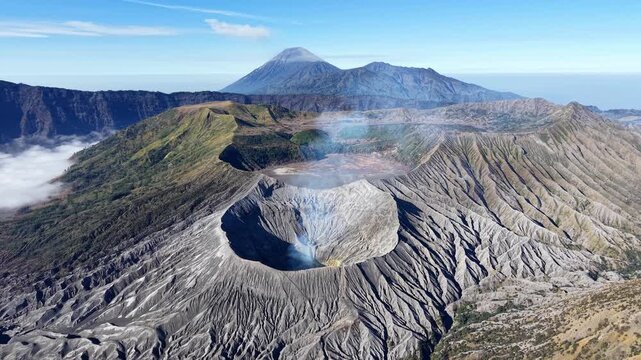 Dramatic sunrise over Mount Bromo crater showing ridged slopes smoke and distant volcanic peaks