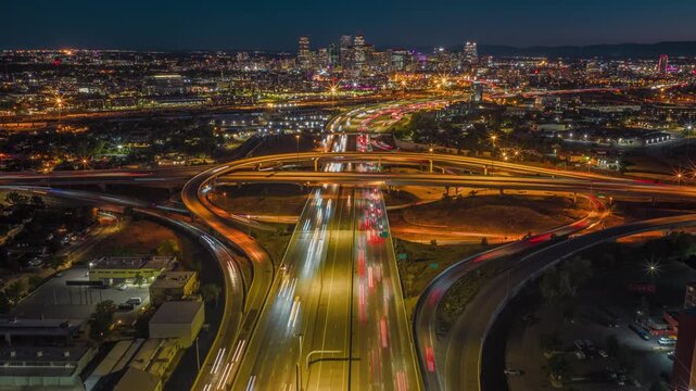 Denver skyline towering over busy interstate highway interchange with light trails drone hyperlapse 4K
