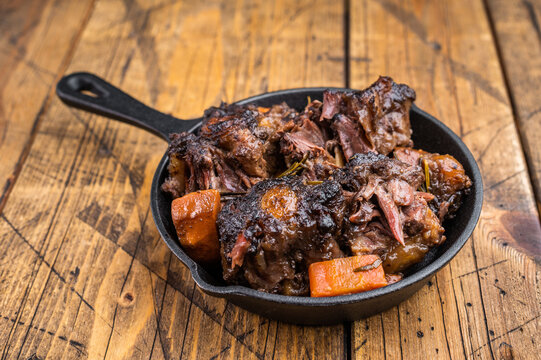 Tender braised oxtail pieces in savory gravy with carrots, gourmet beef stew on wooden background