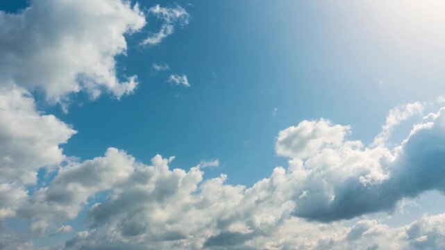 Fluffy white cumulus clouds drifting across a bright blue sky.