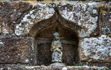 Une petite statue religieuse dans une niche d'un mur du village de locronan en bretagne Finistère France © feuerpferd1111