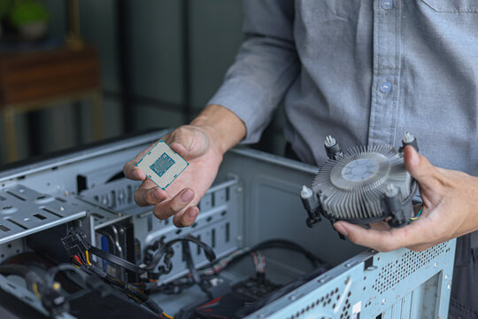 Computer engineer repair and assembling high-performance PC, CPU and cooler at workshop desk.