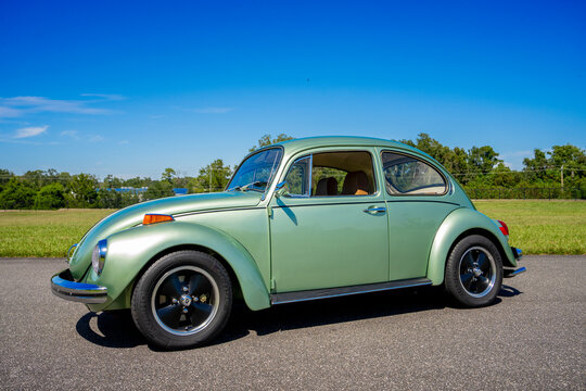 Green color 1971 VW Bug Beetle in an outdoor park setting