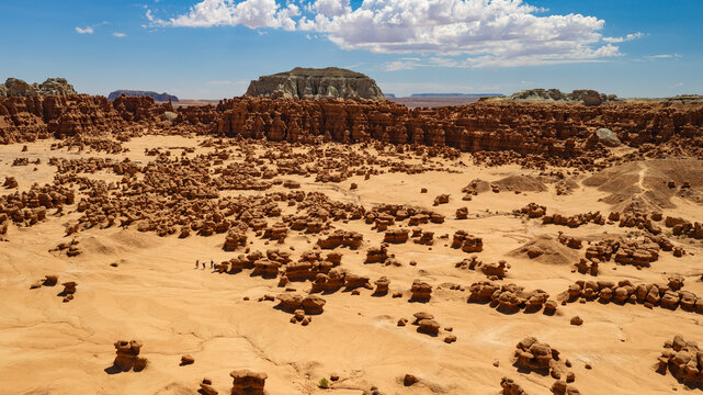 An aerial view of the Valley of the Goblins inside Goblin Valley State Park, Utah. A group of enthusiastic hikers marvel at the enormity of the bizarre terrain.