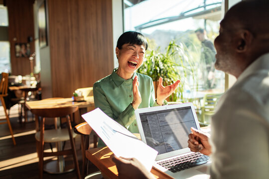 Laughing woman applauds during business meeting in cafe