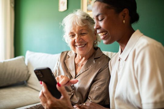 Young woman helping senior use a smartphone at home