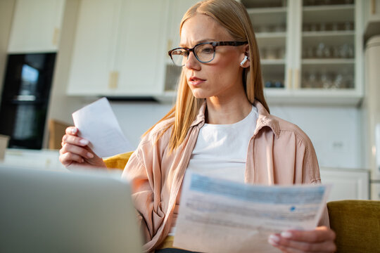 Woman reviewing bills with laptop at home