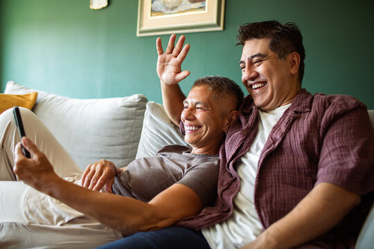 Two men waving on a video call at home