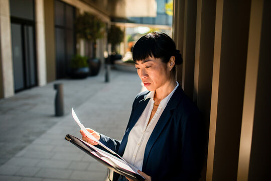 Businesswoman reading documents outside an office building