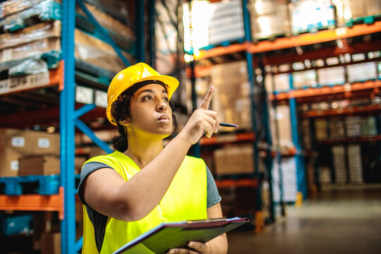 Warehouse worker points while checking inventory with clipboard