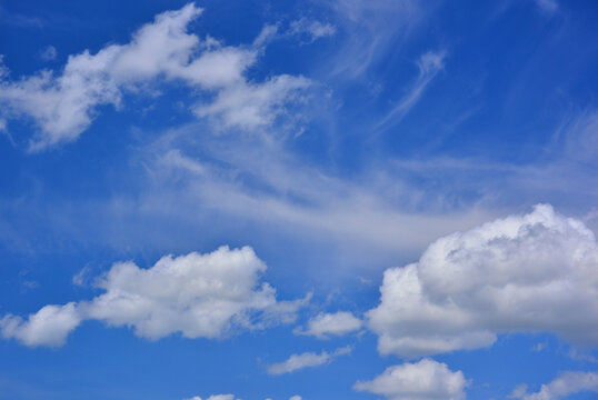 Low cumulus clouds and high cirrus clouds against the deep blue summer sky.