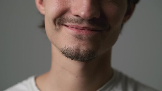 Man smiling with eyes closed in quiet happiness against gray background