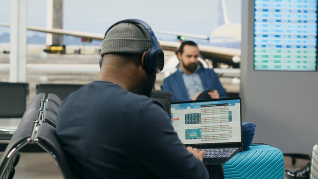 Casual startup representative checks insights and evaluation data on a laptop in an airport lounge, preparing a briefing for an international meeting abroad during a modern global business trip.