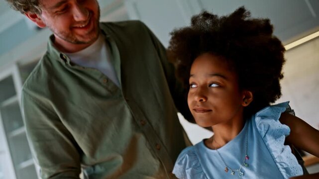 Father whisking eggs with daughter home kitchen. Dad ruffling hair, baking fun.