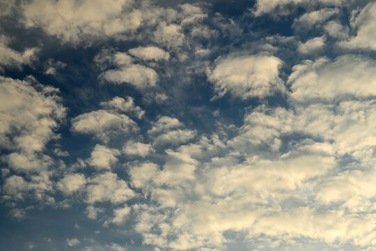 numerous small white cumulus clouds covering a deep blue sky background