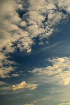 small cumulus clouds lit by golden sunset light against a deep blue sky
