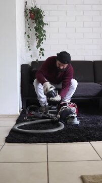 Technician sitting on sofa examining disassembled vacuum cleaner parts at home