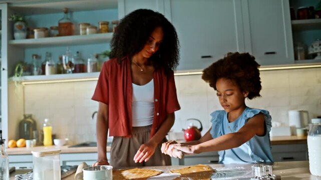 Girl rolling dough with mother home kitchen. African american family baking.
