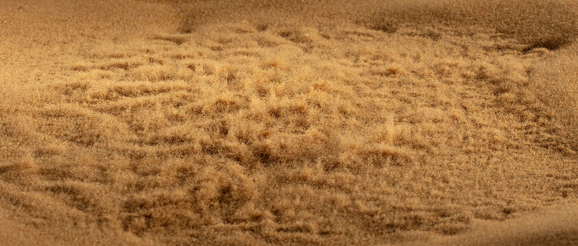 Abstract golden sand dune with glowing powder explosion splatter effects creating futuristic textured particle composition. Dramatic earth sand forms resemble wave shade splash, Photograph