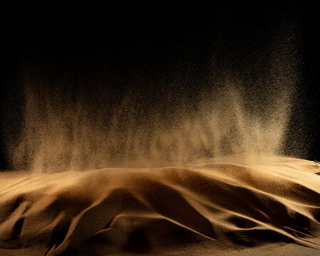 Abstract golden sand dune with glowing powder explosion splatter effects creating futuristic textured particle composition. Dramatic earth sand forms resemble wave shade splash, Photograph