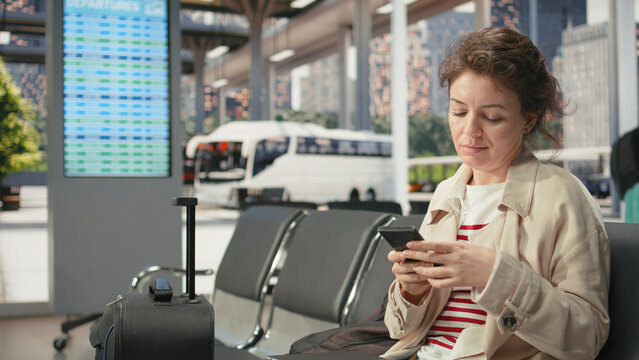 Woman uses notebook in bus terminal while listening to music