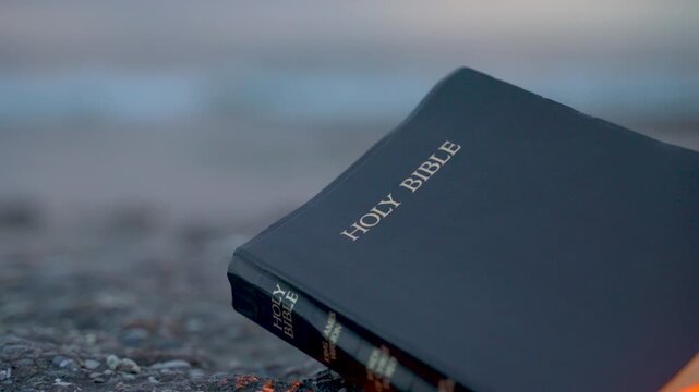 Holy Bible on Rocky Beach with Glowing Golden Light