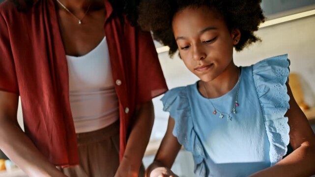 Pressing dough floured board. Multiracial mom daughter baking cookies kitchen.