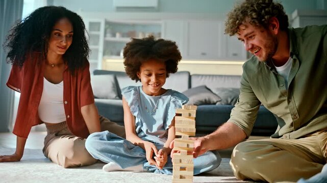 Wooden block tower game floor. Daughter parents playing board living room.