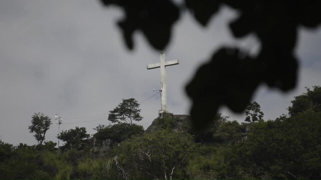 a giant cross on the summit of a wooded mountain
