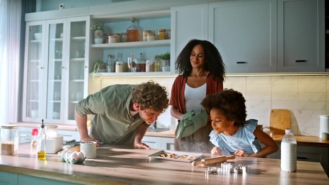 Parents daughter high five over fresh baked cookies. Happy family kitchen fun.
