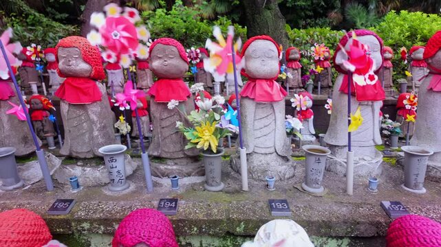 Stone Jizo statues with red hats and pinwheels at Zojoji Temple in Minato, Tokyo, Japan, placed in prayer for the souls of children.