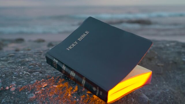 Holy Bible on Rocky Beach with Glowing Golden Light