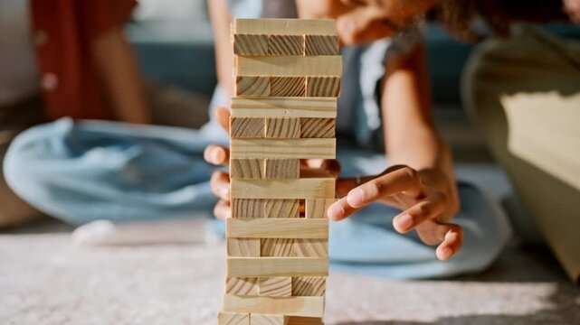 Smiling kid pulling wooden block from tower. Close up family board game home.
