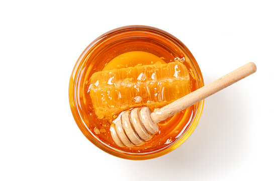 Flat lay of organic golden honey in a glass bowl, featuring a fresh honeycomb and a wooden dipper. Clean minimalist food photography isolated on a white background.